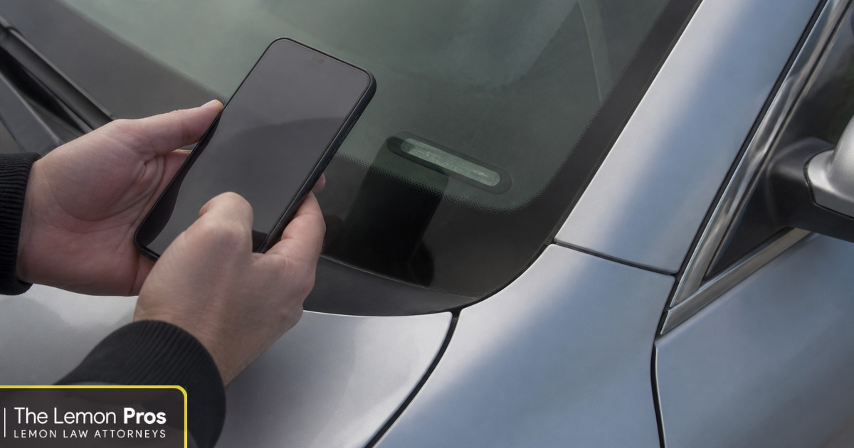 Check the recall against your own VIN, not the model Hands holding a smartphone beside the lower corner of a car windshield where the vehicle identification number plate is located