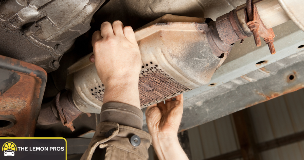 Mechanic inspecting a catalytic converter under a vehicle during a warranty evaluation.